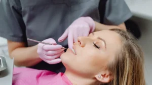 Dentista examinando os dentes de uma paciente deitada na cadeira odontológica